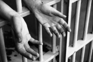 Hands in prison cell --- Image by © Ocean/Corbis